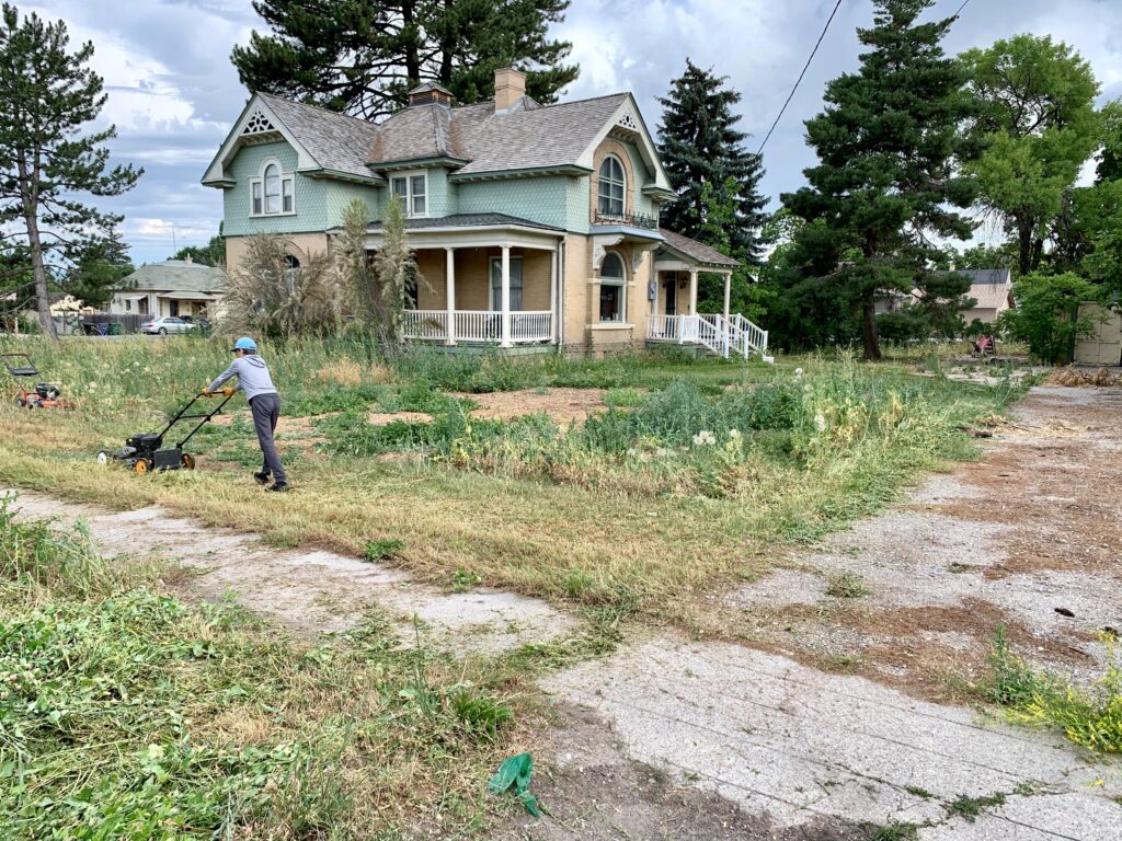 Man cutting grass around his house